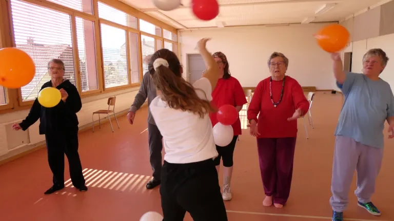 Personen in Bewegung spielen mit bunten Luftballonen